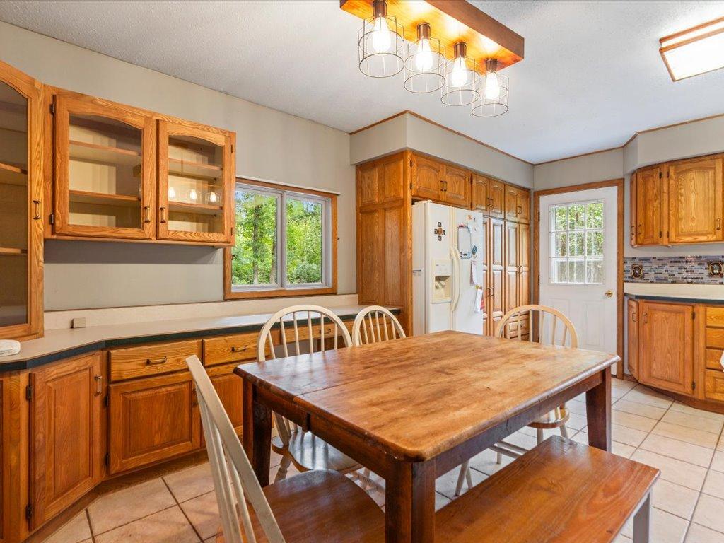 Kitchen and dining area with wood cabinetry, a large dining table, and a window overlooking trees.