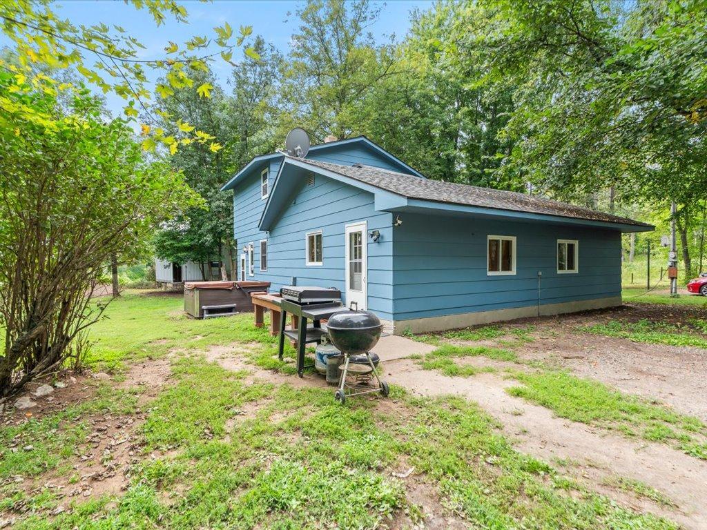 Blue-sided house with a long low roof, backyard grill, and leafy trees.
