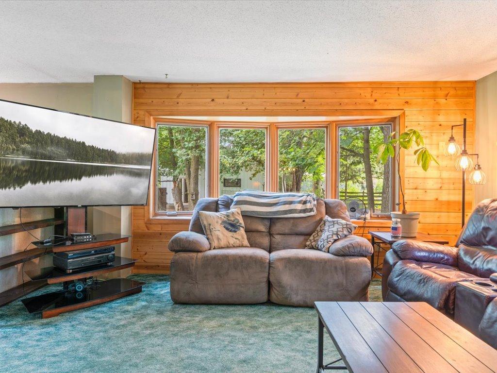 Living room with wood-paneled walls, large windows, and a central reclining sofa.