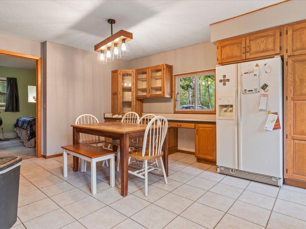 Kitchen and dining area with oak cabinets, white refrigerator, and a wooden table with white chairs.