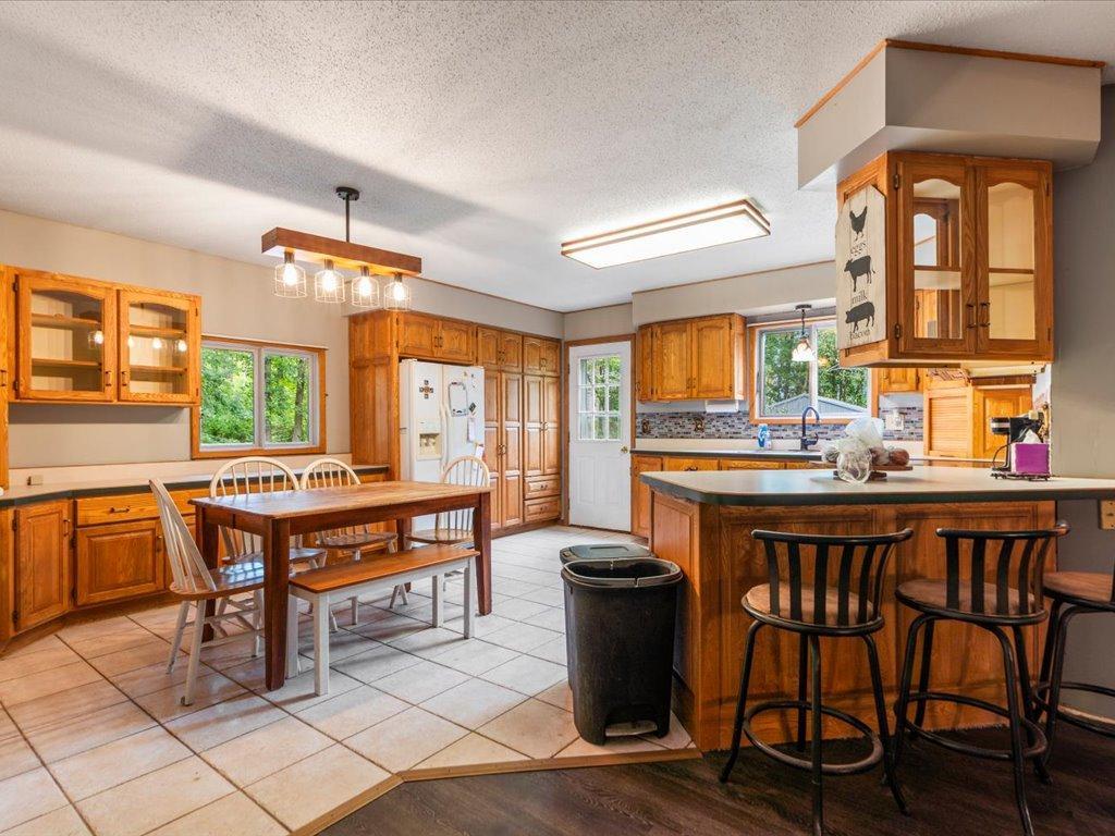 Kitchen with extensive wood cabinetry, a central island with bar seating, and an adjoining dining area.