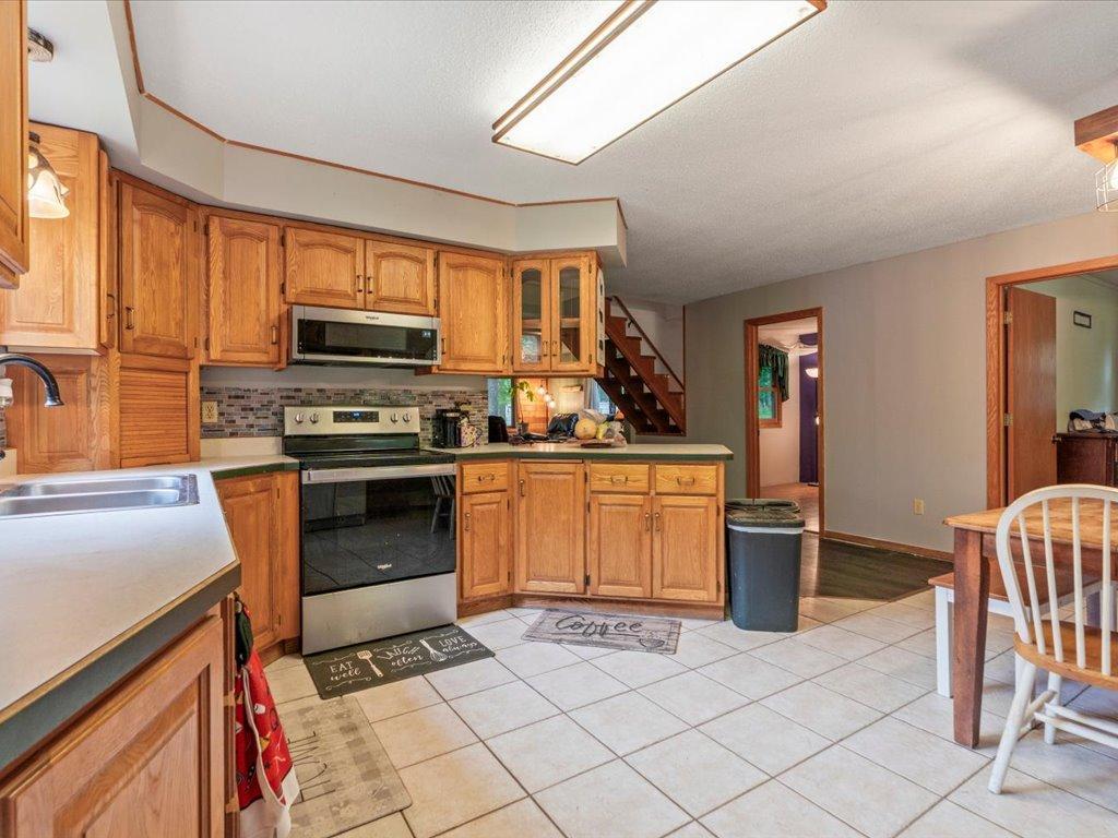 Kitchen with honey-toned wood cabinets, stainless steel appliances, and a tiled floor.