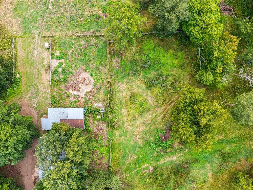 Aerial view of a wooded property with a small outbuilding and open grassy land.