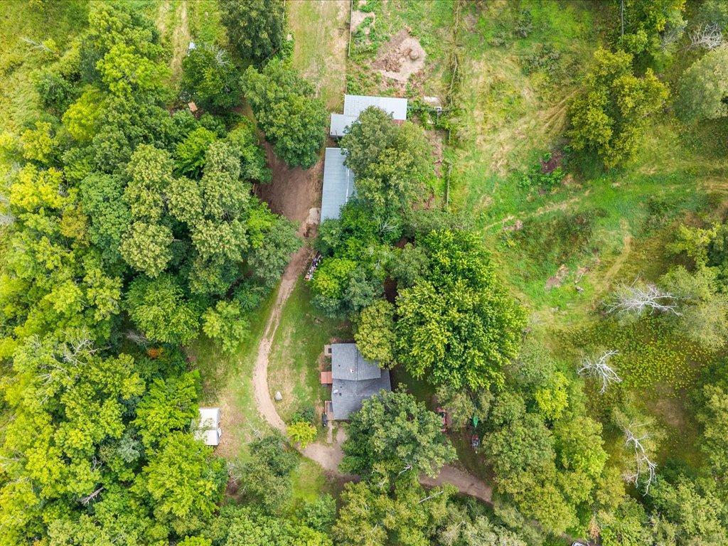 Aerial view of a wooded property with two buildings and a winding driveway.