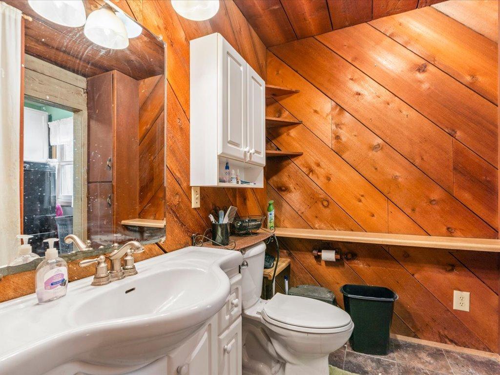 Bathroom with a white sink and toilet against warm diagonal wood paneling.