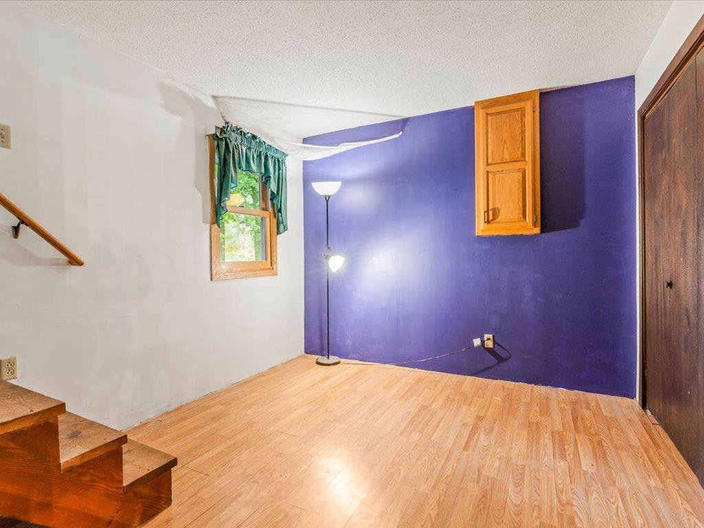 Room with purple accent wall, wood flooring, a window, and stairs.