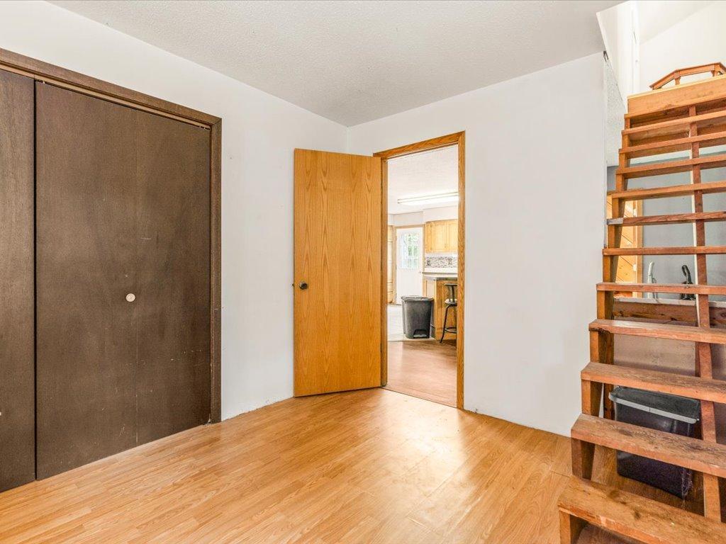 Entry hall with wood flooring, a dark closet door, and open-riser stairs.