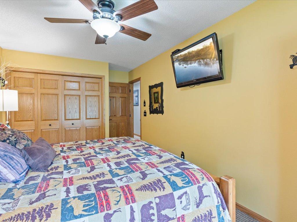 Bedroom with a colorful patchwork quilt, wooden closet doors, and a wall-mounted television.