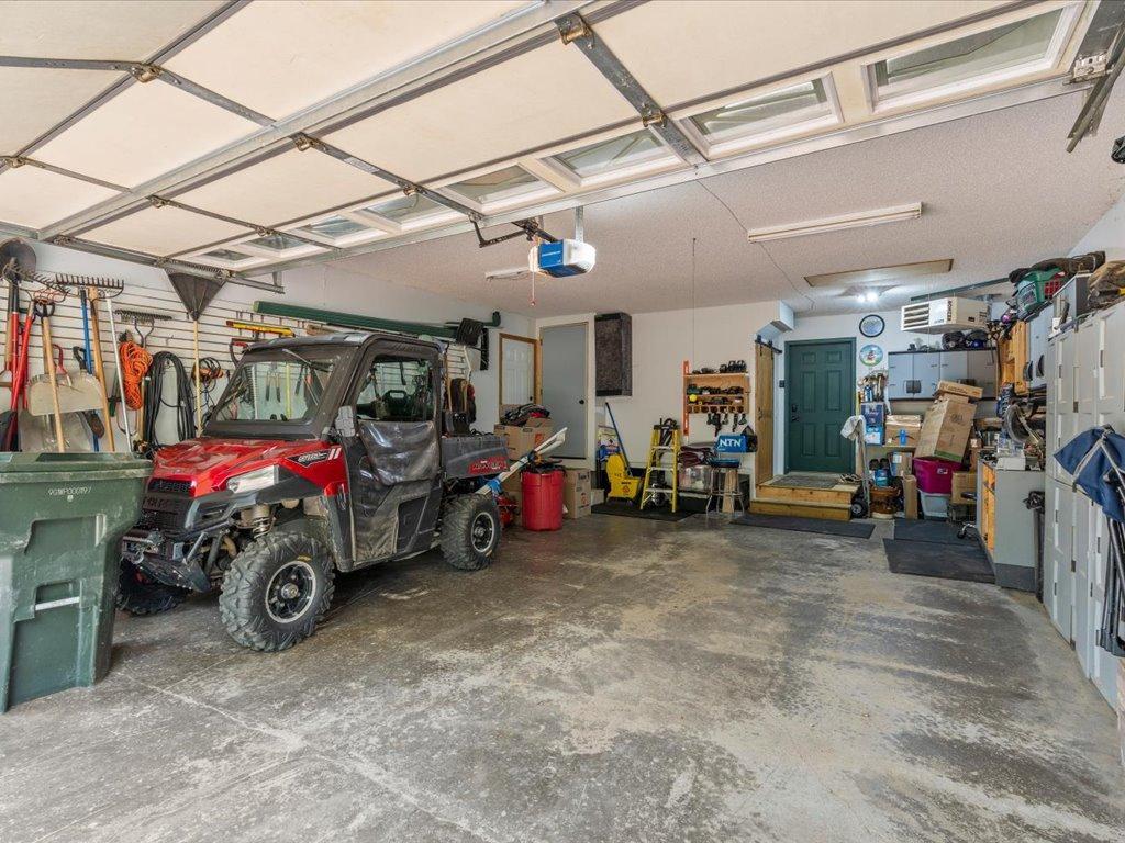 Spacious garage with a windowed overhead door, side-by-side utility vehicle, and extensive storage.