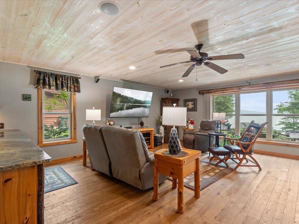 Living room with recliners, a wood-plank ceiling, and large windows overlooking the lake.