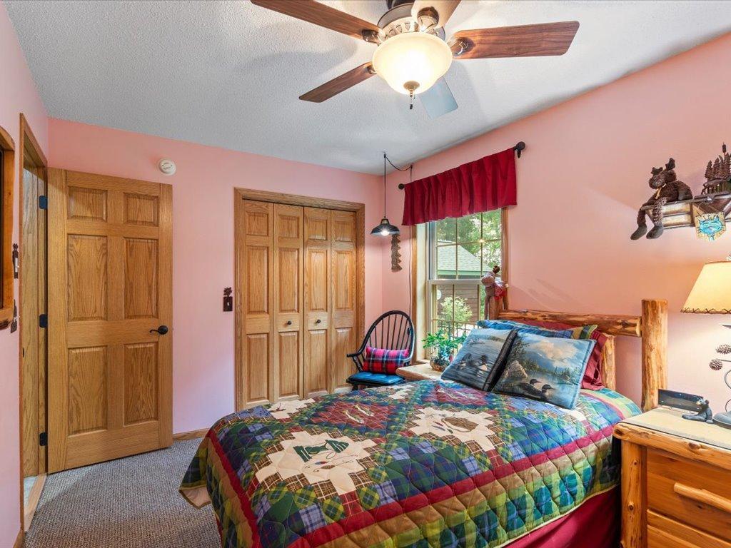 Bedroom with pink walls, wooden closet doors, and a colorful patchwork quilt on the bed.