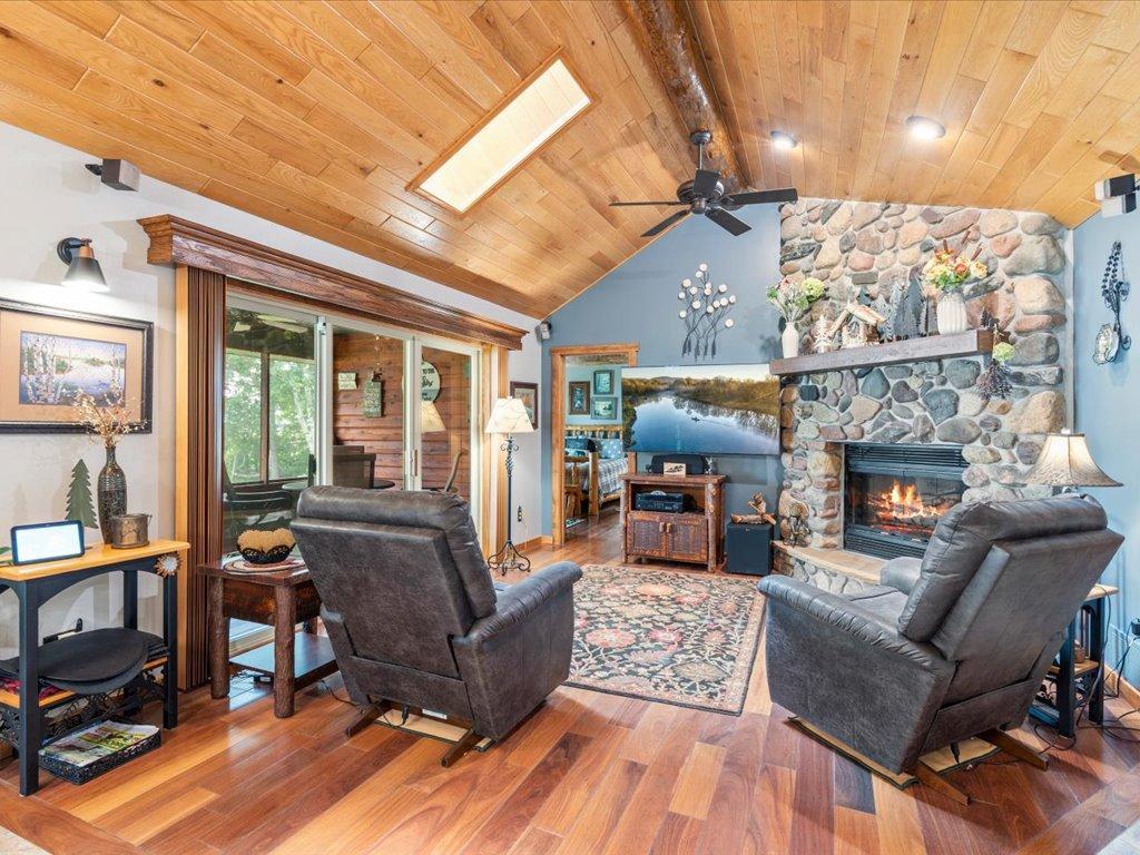 Living room with a vaulted wood ceiling, stone fireplace, and two leather recliners.