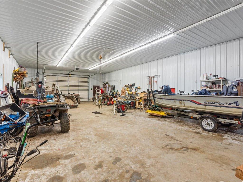 Spacious garage workshop with an ATV, boat, tools, and workbenches.