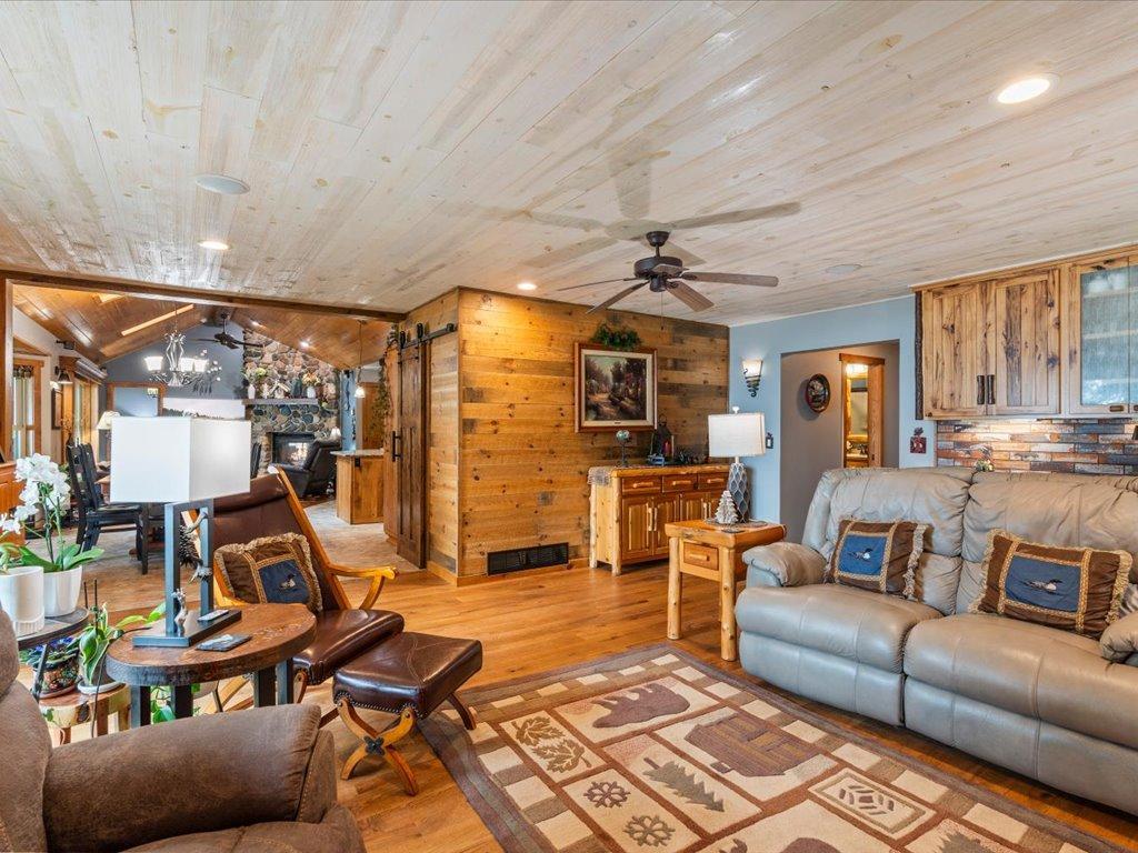 Living room with a wood-plank ceiling, leather seating, and a stone fireplace.