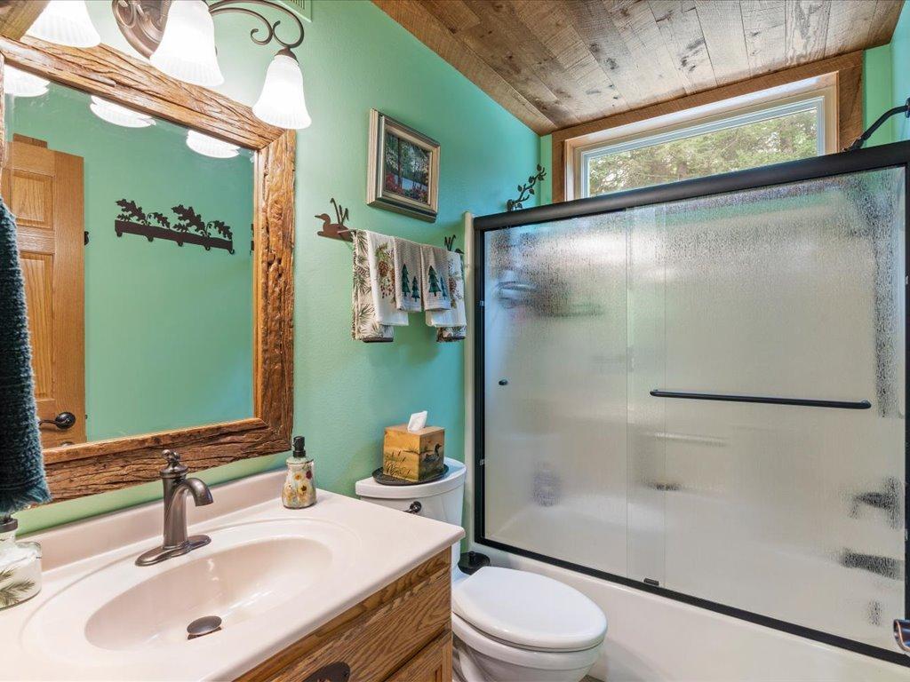 Bathroom with a frosted-glass shower, white vanity, and rustic wood trim.
