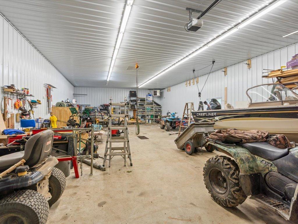 Spacious workshop garage with boats, ATVs, and equipment stored inside.