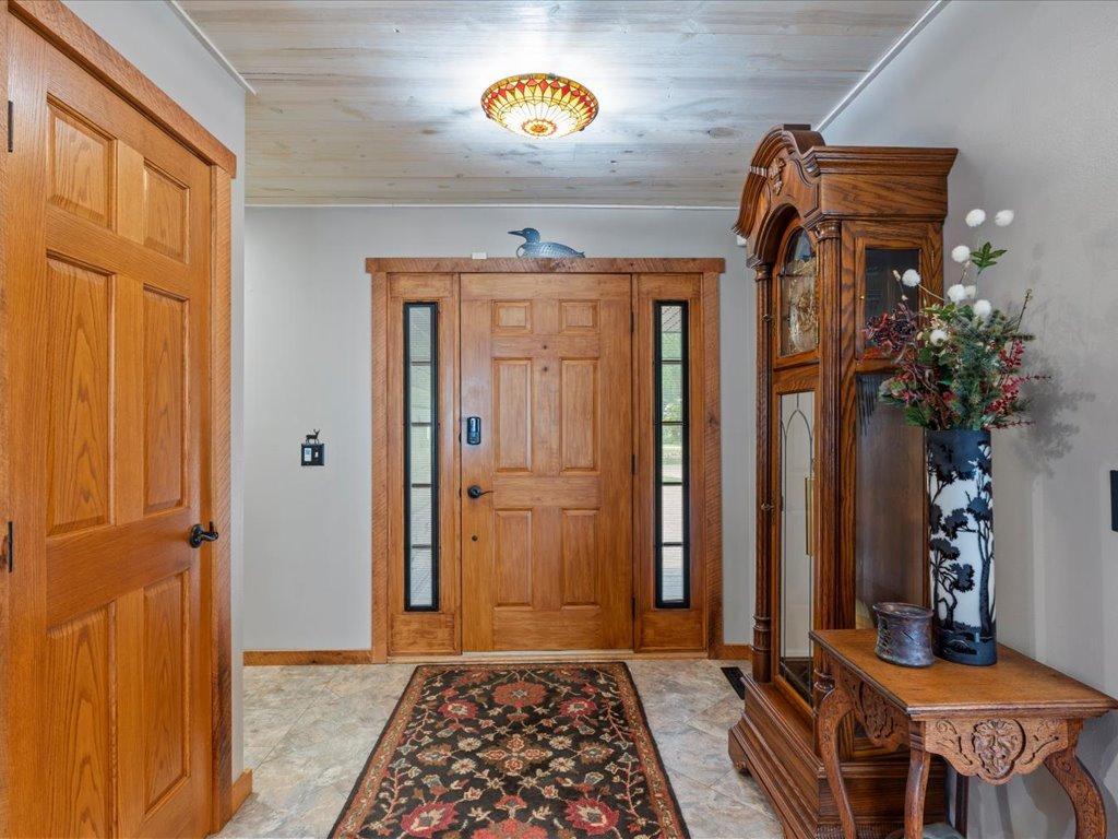 Entry foyer with a wood front door, narrow sidelights, tiled floor, and ornate cabinet.