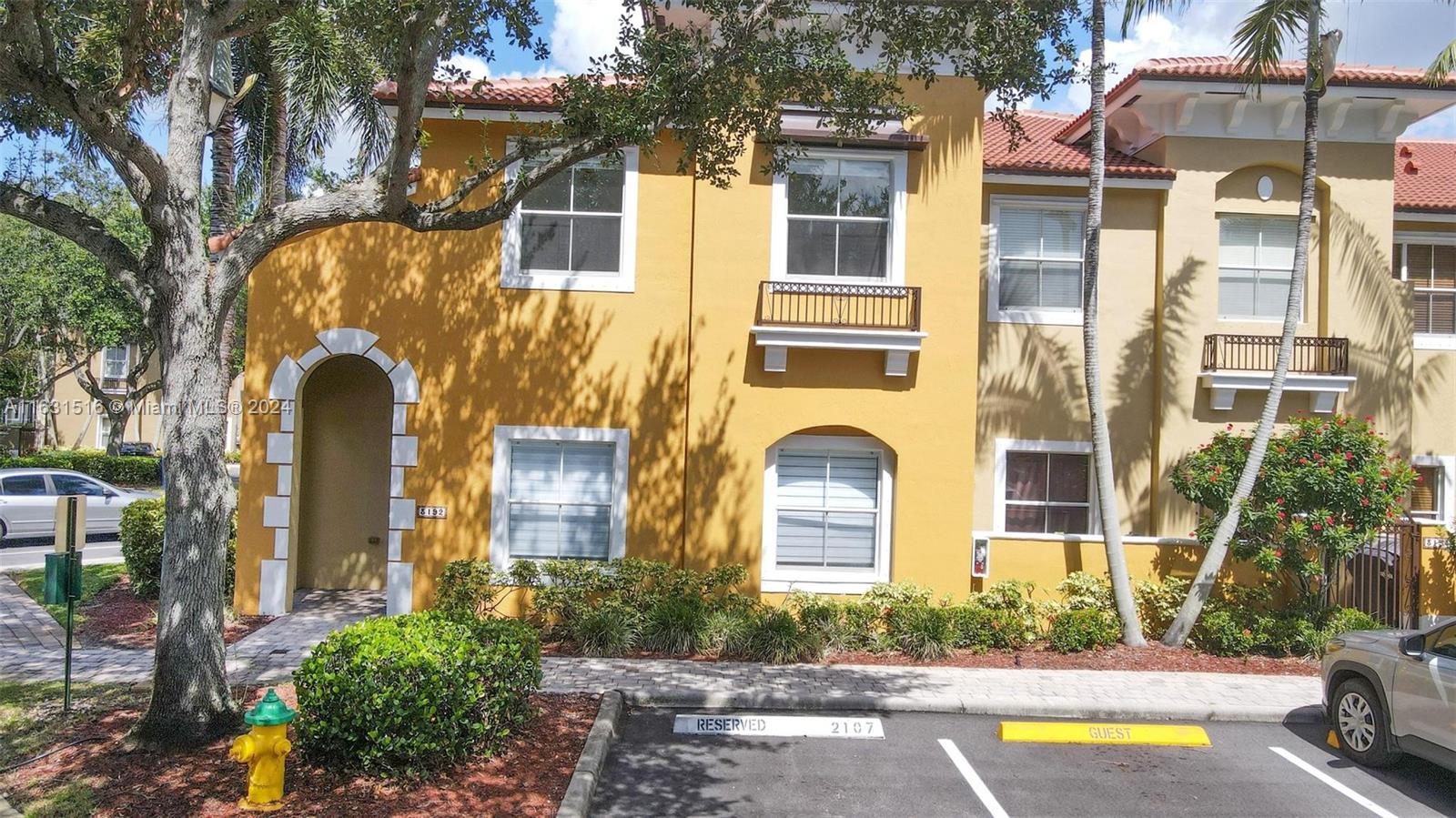 Yellow townhouse exterior with an arched entry, red tile roof, and reserved parking space 2107.