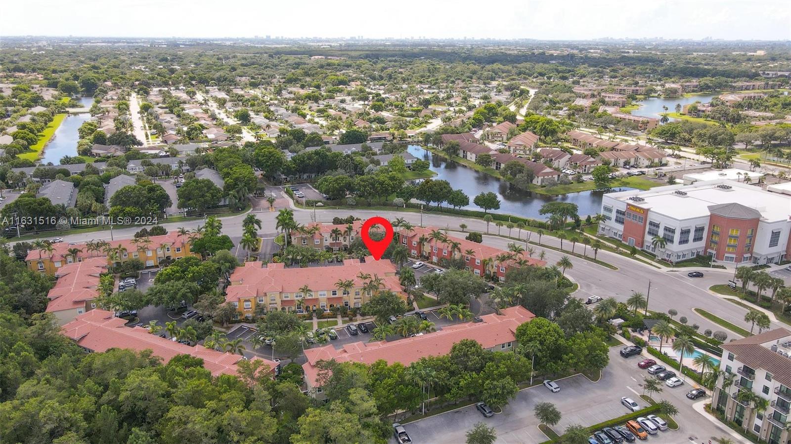 Aerial view of a townhouse community beside waterways, with a red marker identifying one building.