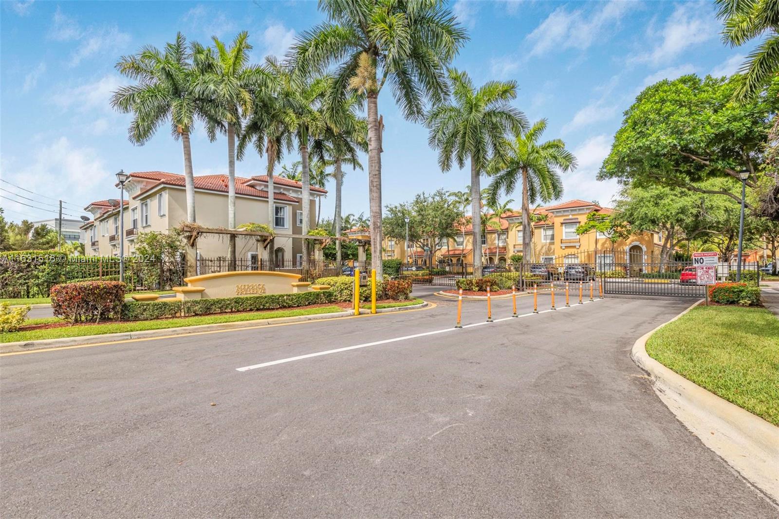 Merrick Preserve community entrance with a gated road, palm trees, and townhouses.