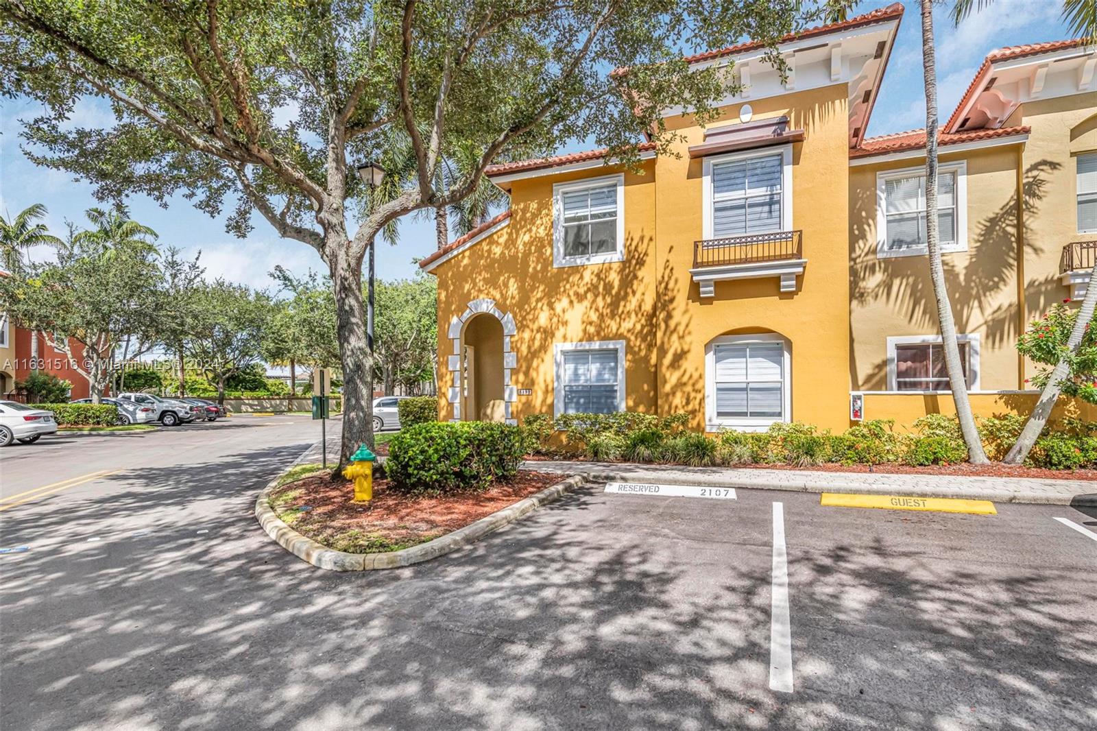 Yellow townhouse-style condominium exterior with an arched entrance and reserved parking space 2107.