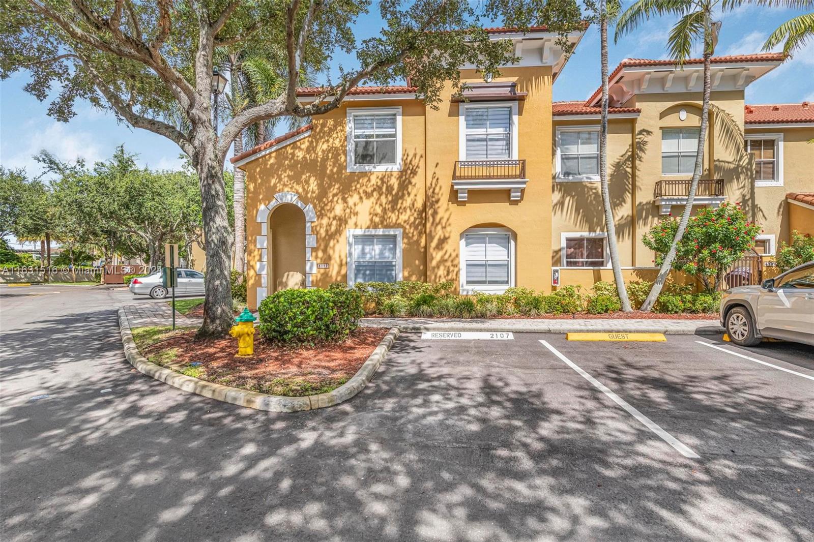 Yellow stucco townhouse with an arched entrance and parking space marked 2107.