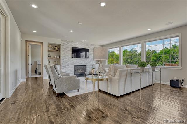 Living room with light sofas, a fireplace, large windows, and dark wood floors.