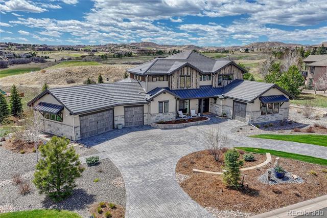 Two-story stone-and-siding home with multiple garage bays and a broad driveway, surrounded by open terrain.