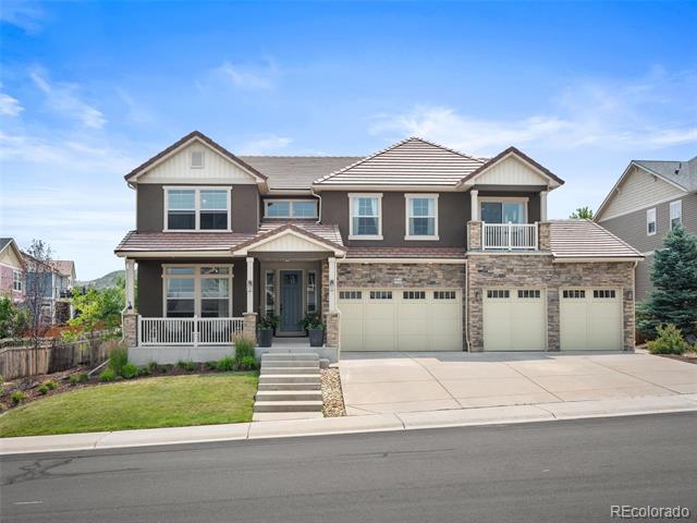 Two-story home with stone accents, a covered porch, upper balcony, and three-car garage.