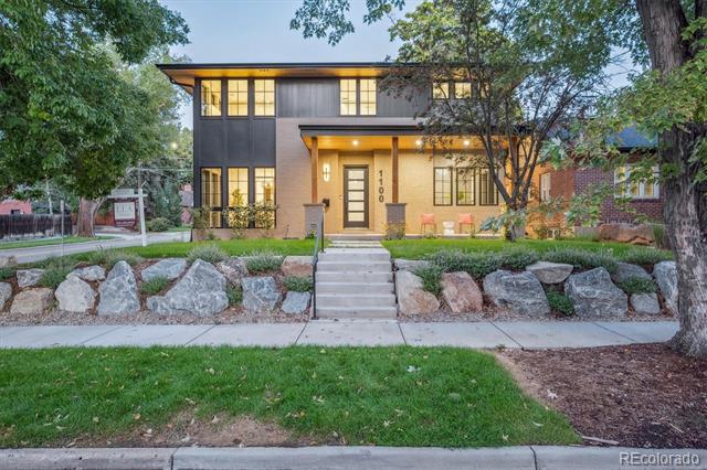 Modern two-story home with a warmly lit entry, broad front steps, and a stone retaining wall.