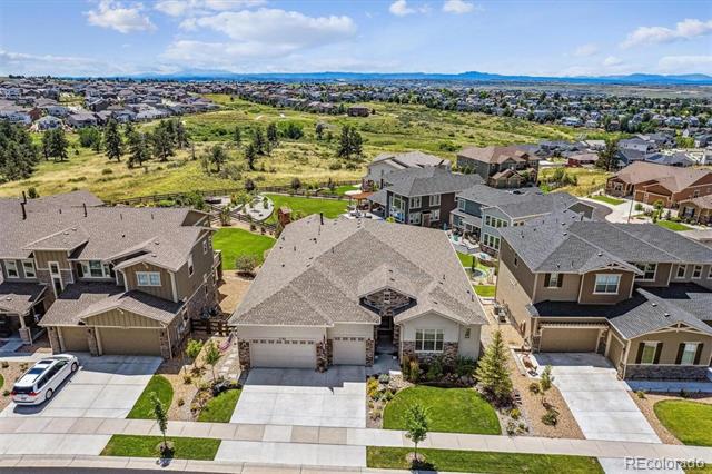 Aerial view of suburban homes beside a green open space, with distant mountains.