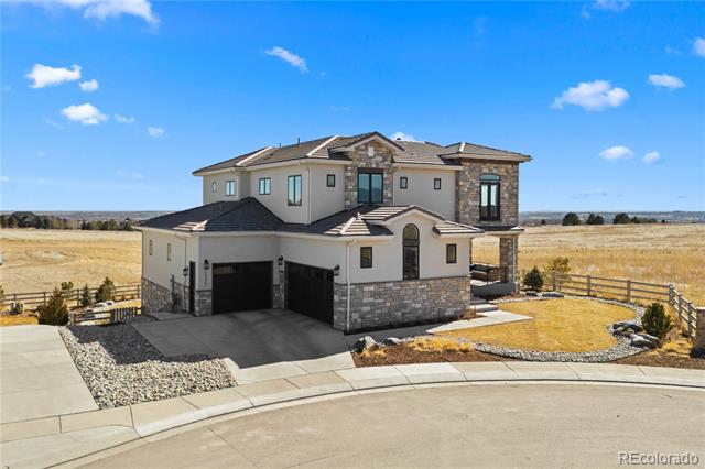 Two-story stucco and stone home with twin garage doors on an open, landscaped lot.