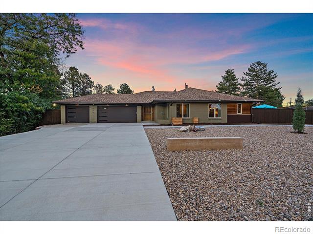 Single-story home with a two-car garage, broad driveway, and gravel landscaping at dusk.