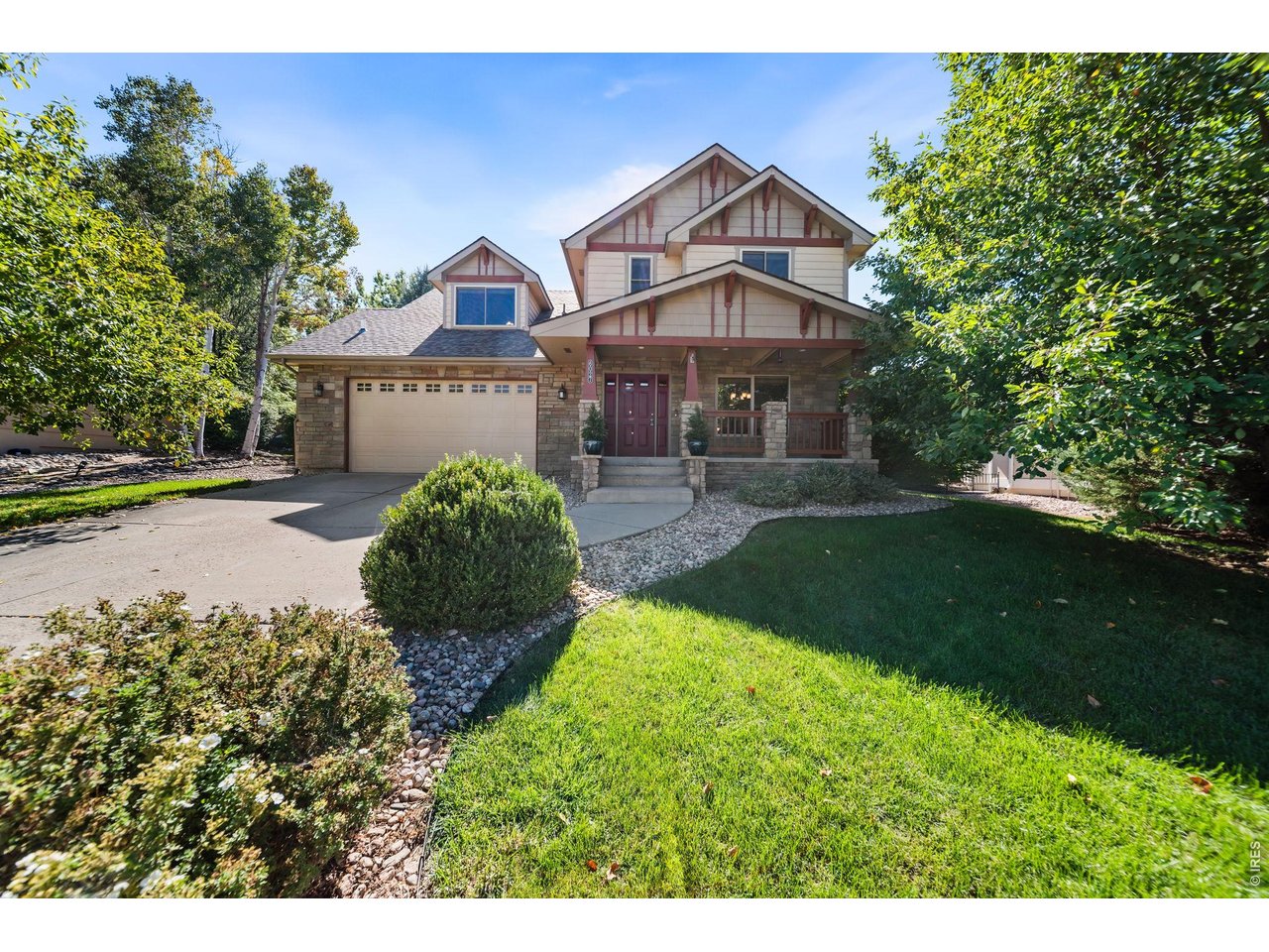Two-story house with a stone facade, covered porch, attached garage, and landscaped front lawn.