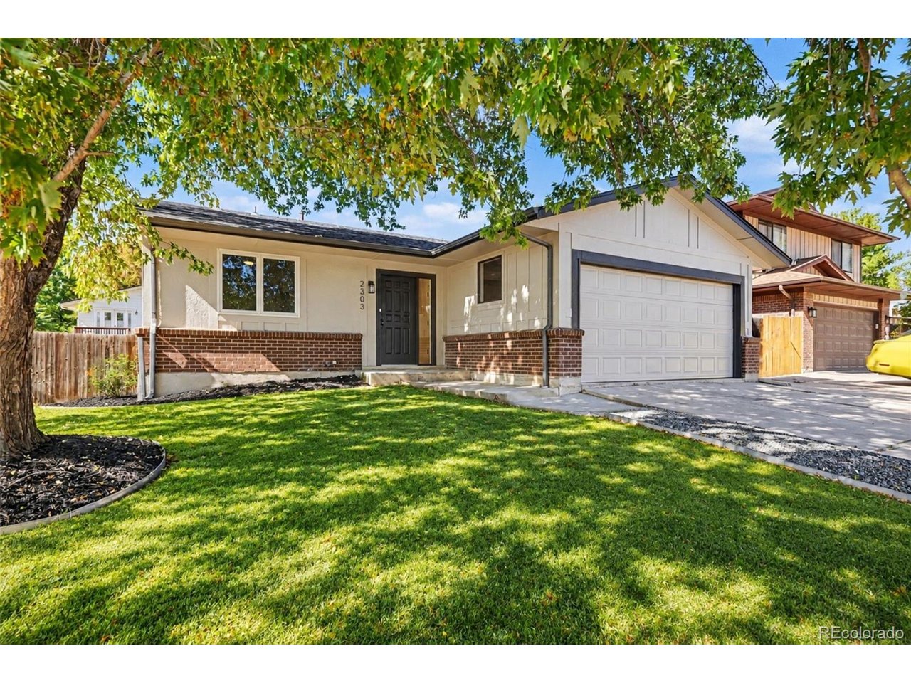 Single-story house with brick accents, attached garage, and a shaded front lawn.
