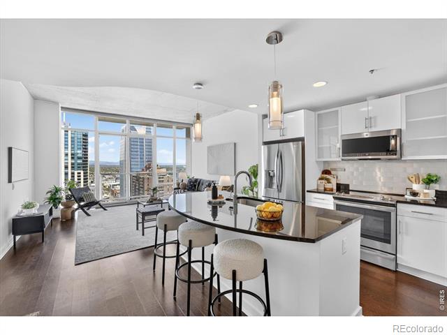 Open-plan condo kitchen with a dark island and floor-to-ceiling windows overlooking the city.