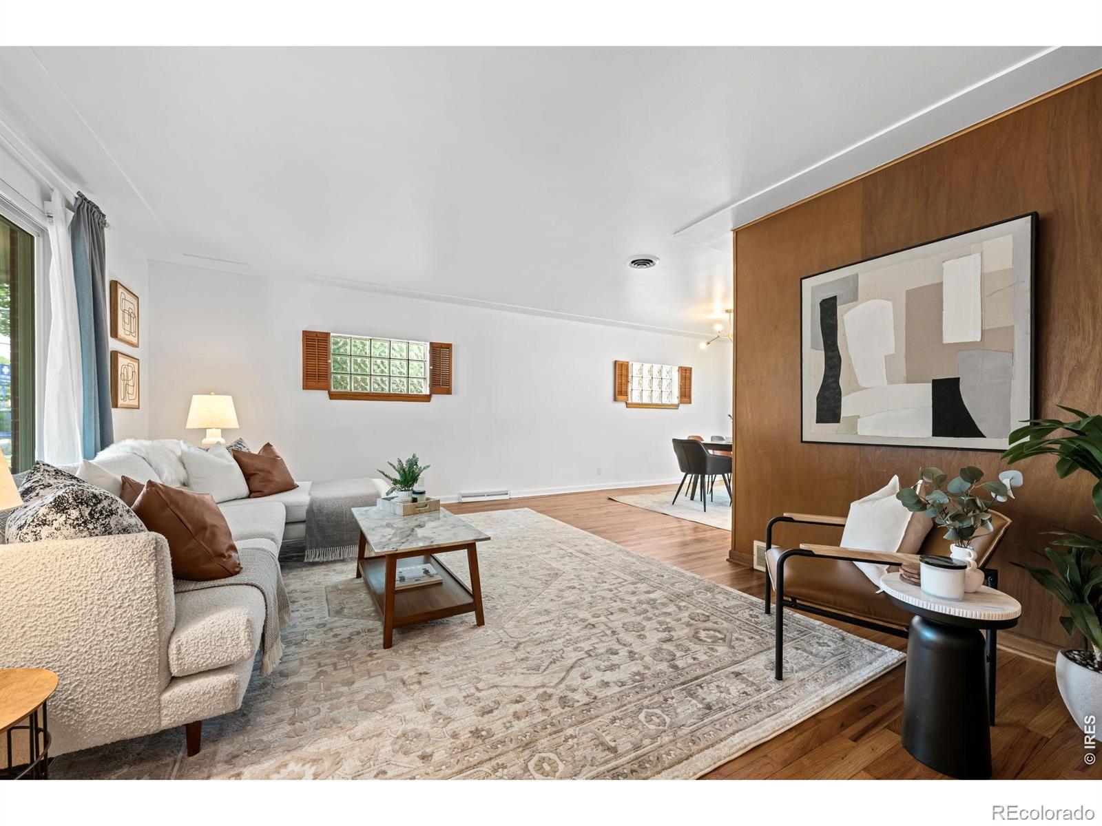 Furnished living room with a white sectional, patterned rug, and wood-paneled accent wall.