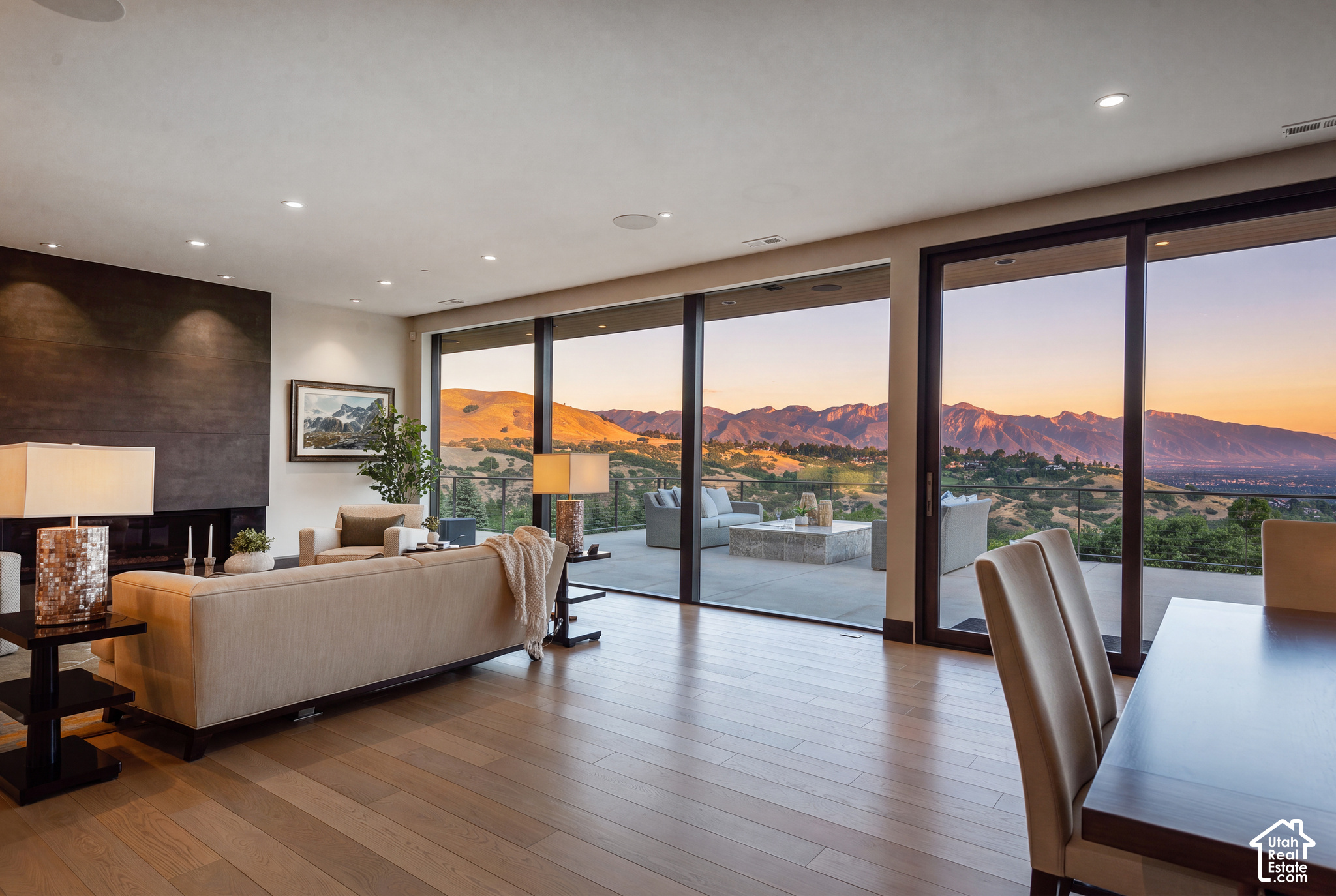 Living room with floor-to-ceiling windows overlooking mountains at sunset.