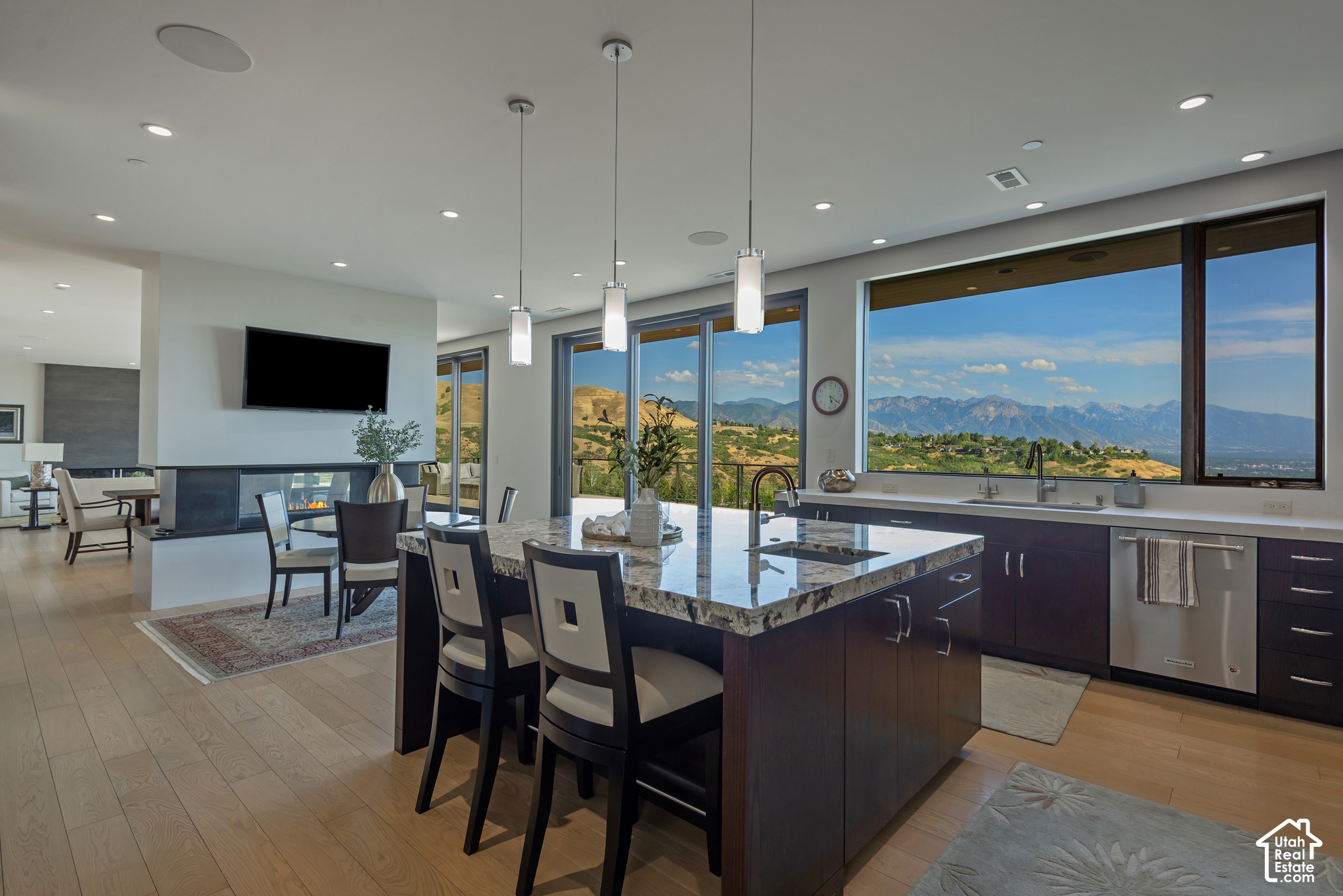 Open-plan kitchen with a large stone island and mountain views through floor-to-ceiling windows.
