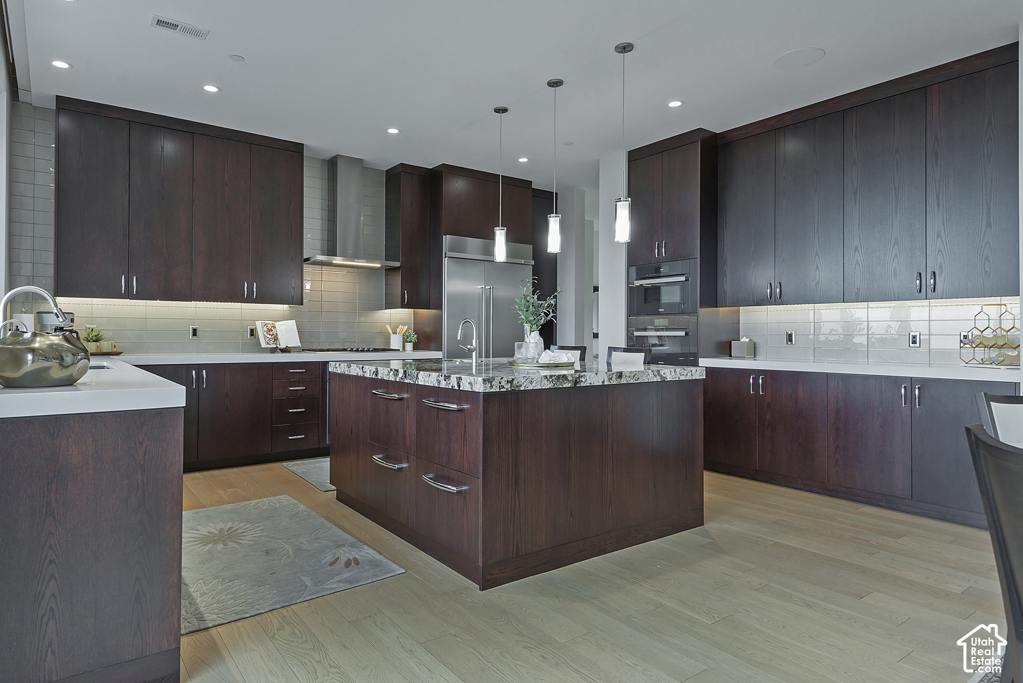 Modern kitchen with dark wood cabinetry, stainless appliances, and a large granite-topped island.