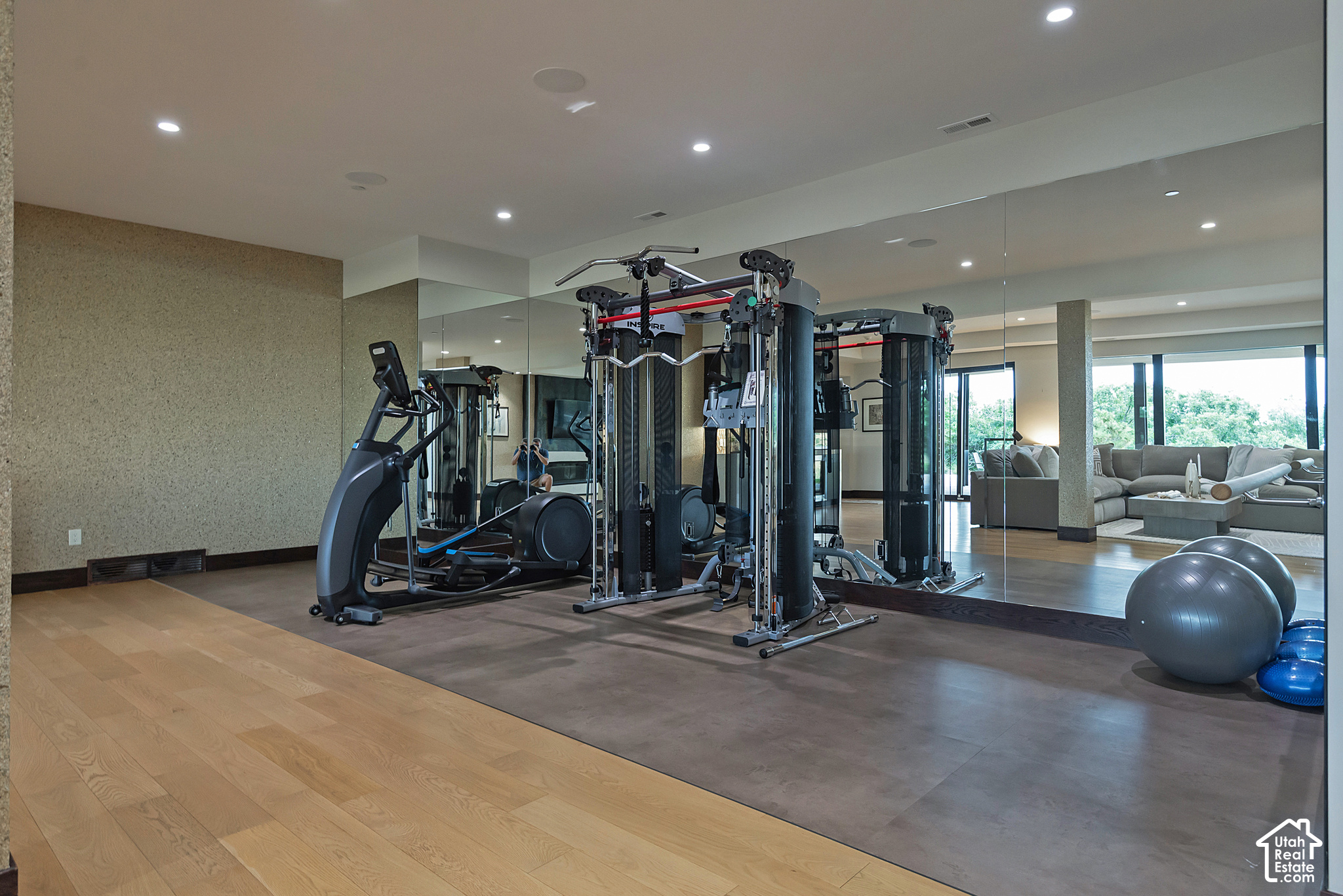 Home gym with mirrored walls, weight machines, exercise balls, and an adjoining lounge.