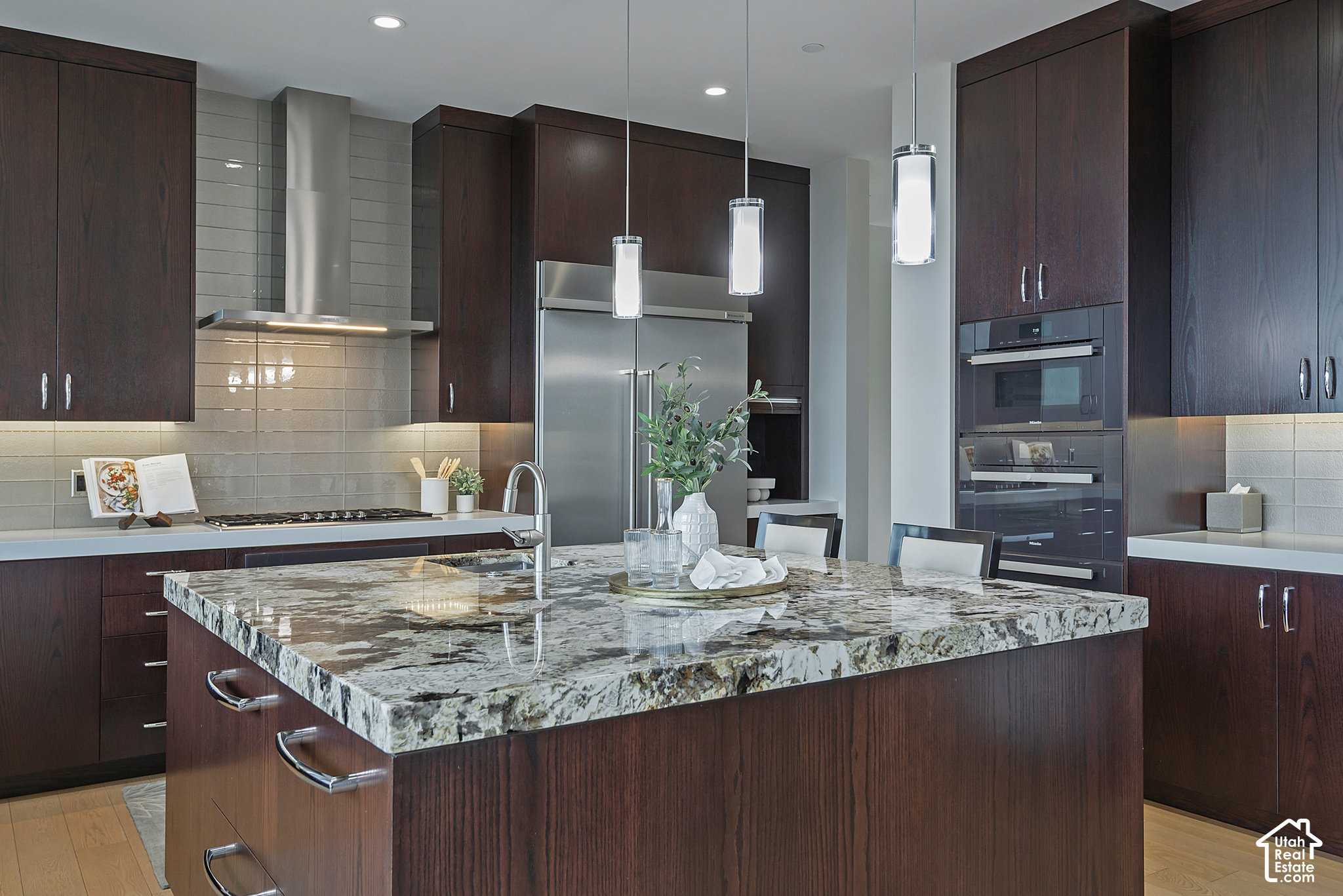 Modern kitchen with dark wood cabinets, stainless steel appliances, and a large granite island.
