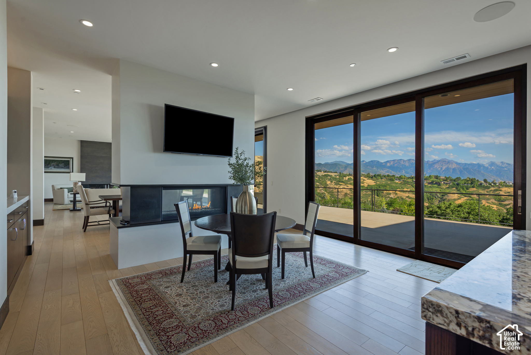 Dining area with a modern fireplace and floor-to-ceiling doors overlooking the mountains.