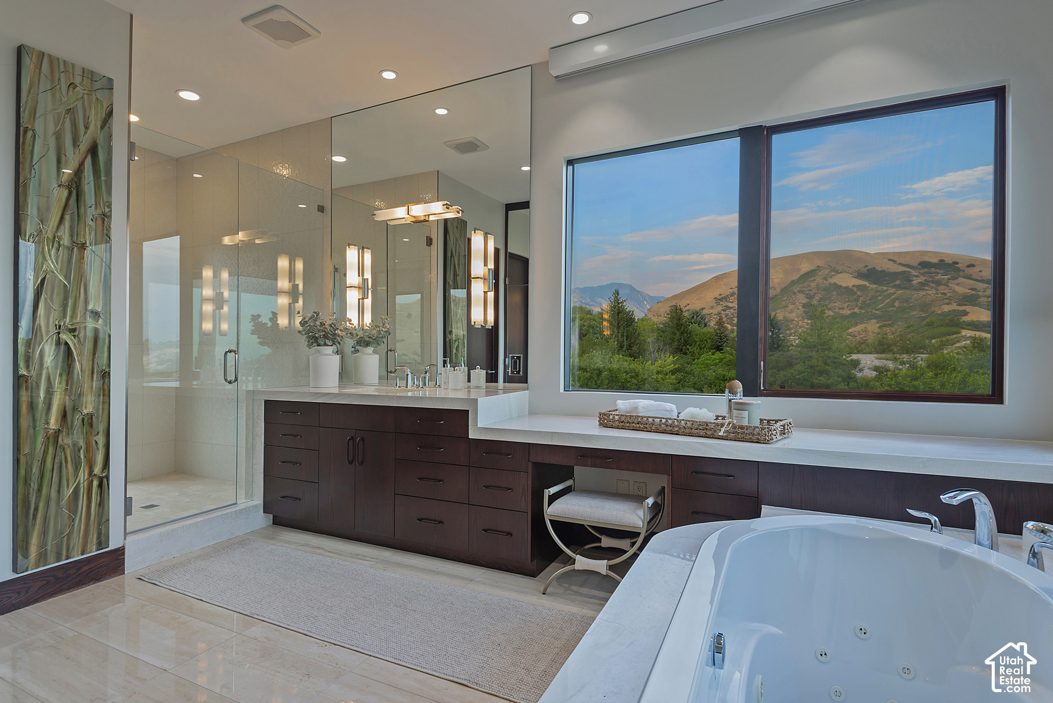 Modern bathroom with a soaking tub, glass shower, dark wood vanity, and mountain views through a large window.