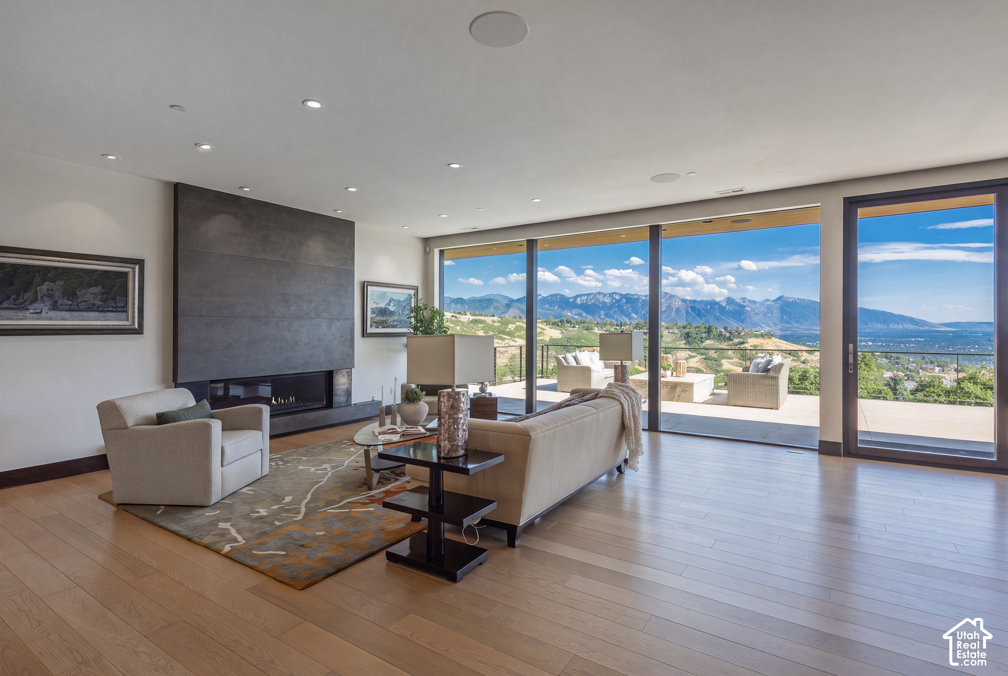 Living room with a dark stone fireplace and floor-to-ceiling windows overlooking mountains.