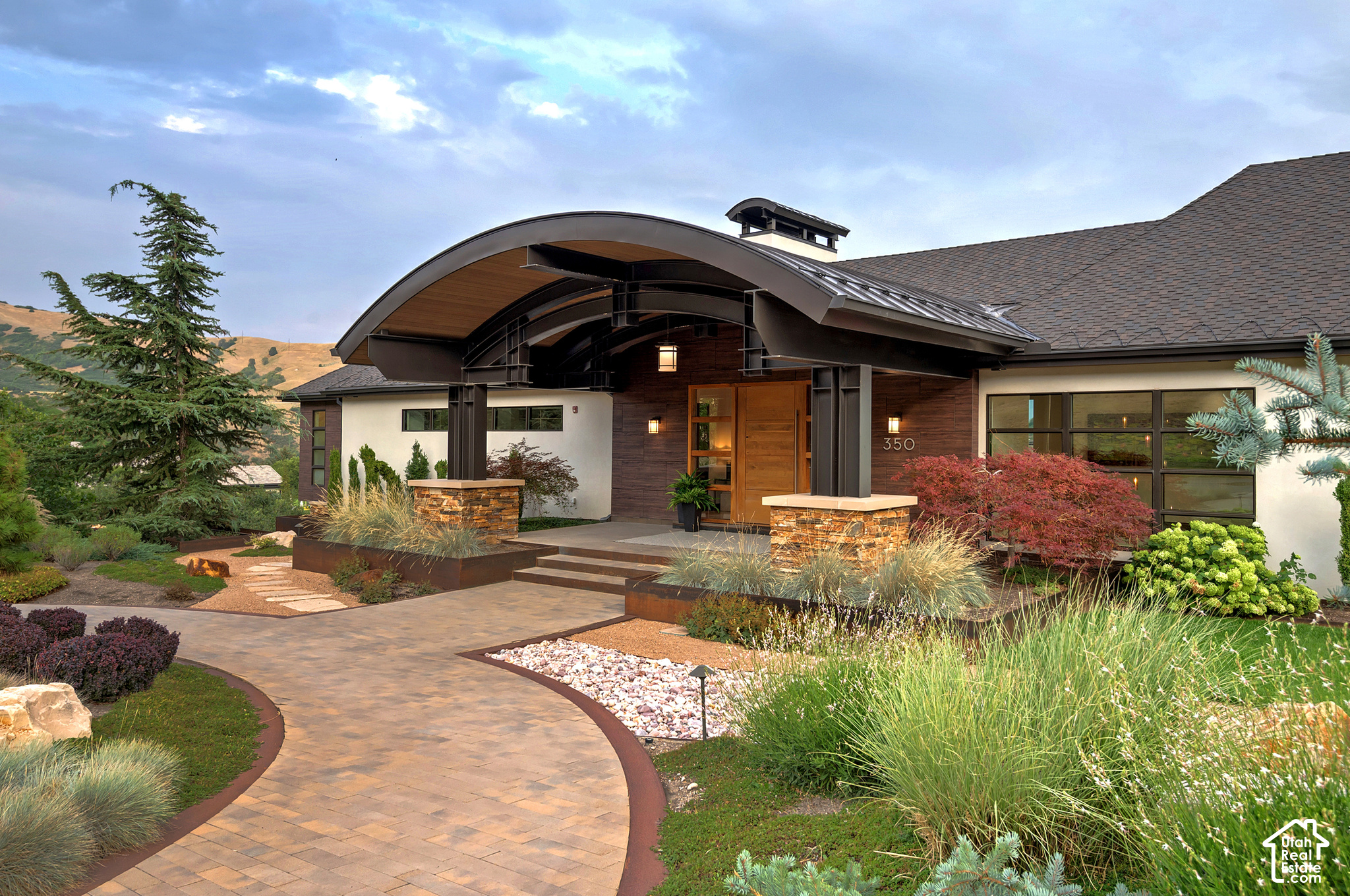 Modern home with a curved entrance canopy, wood front door, and landscaped walkway.