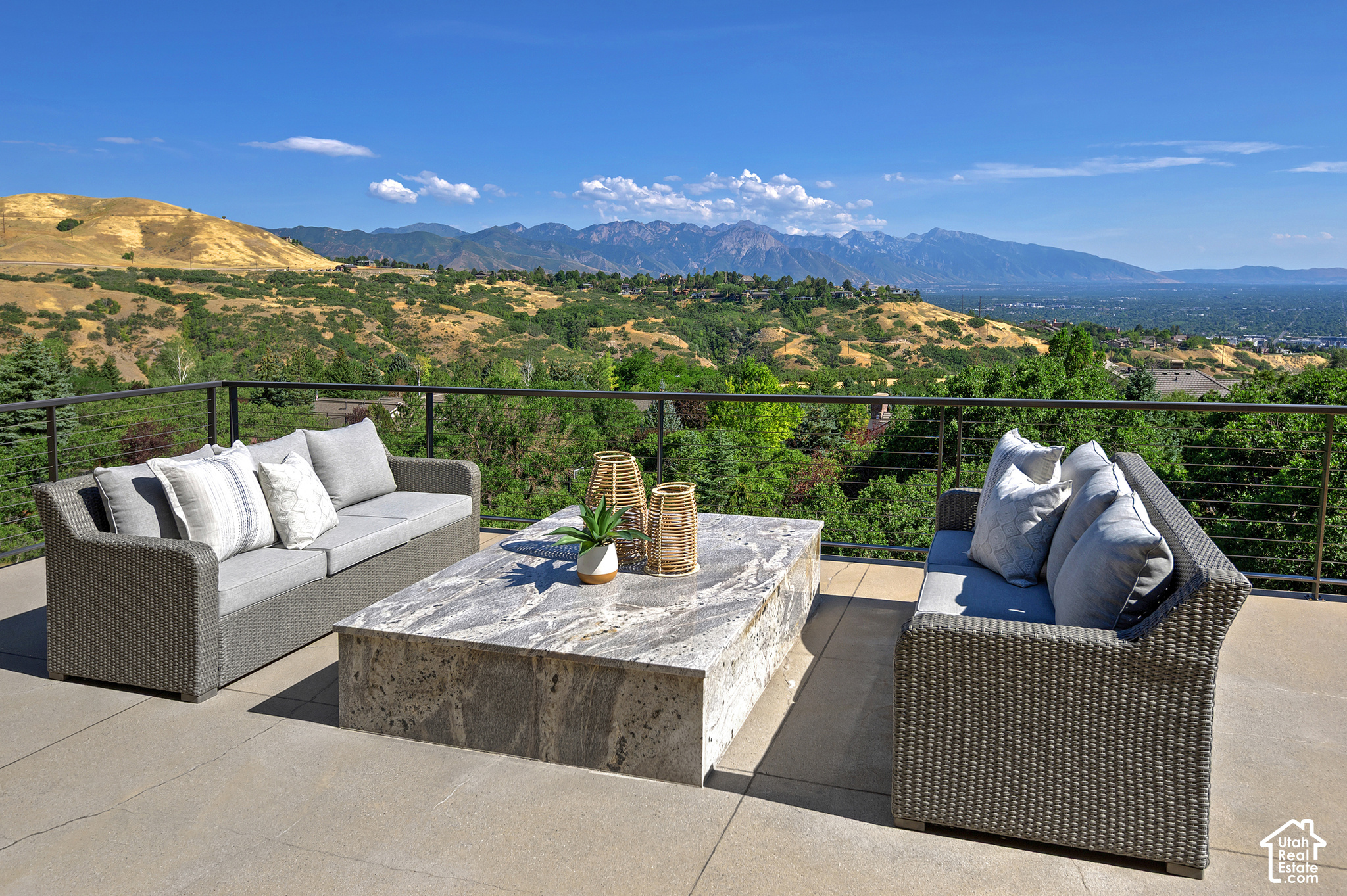 Furnished terrace with mountain and valley views, wicker seating, and a stone coffee table.