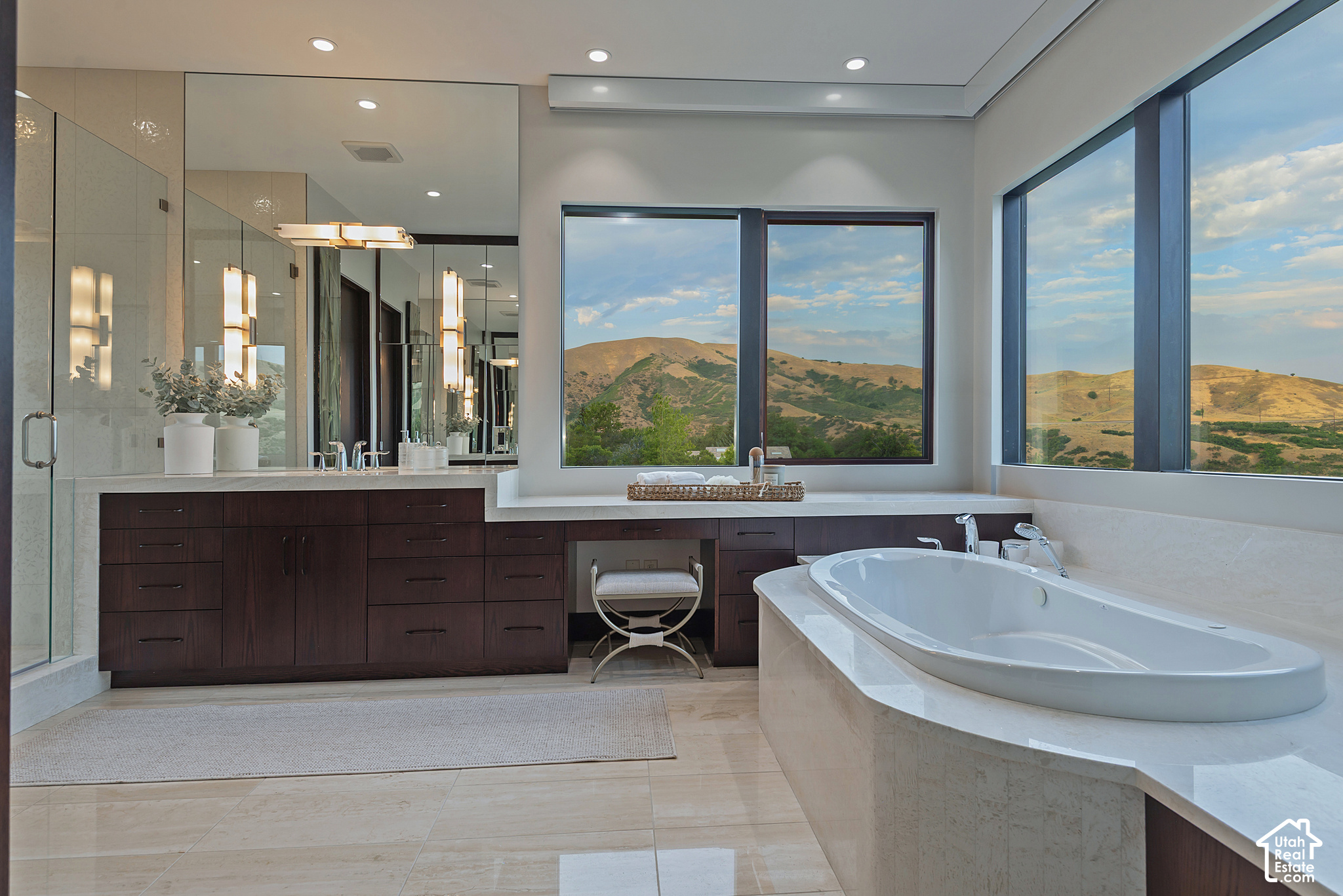 Modern bathroom with a freestanding soaking tub and large windows overlooking rolling hills.