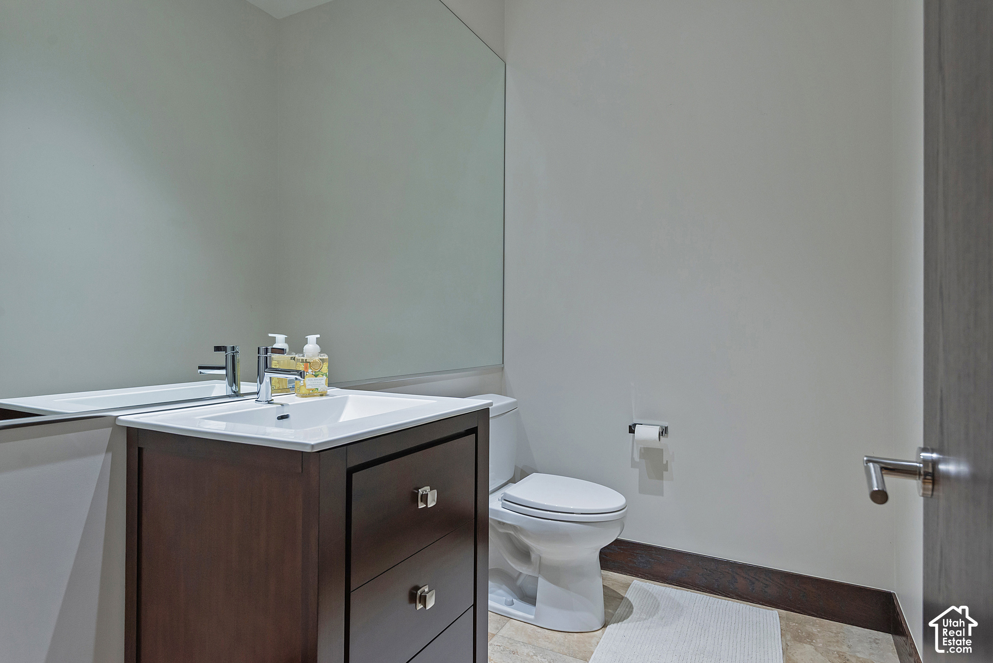 Bathroom with dark wood vanity, white sink, large mirror, and toilet.
