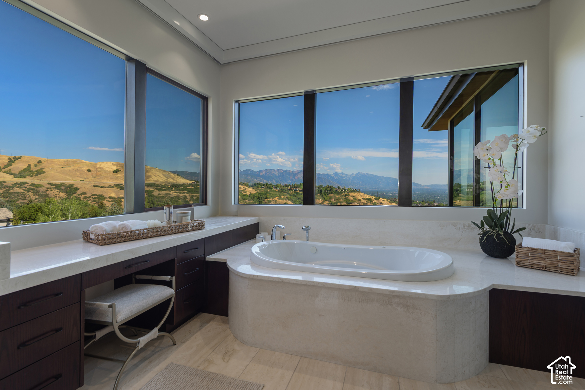 Bathroom with a built-in soaking tub and expansive windows framing mountain views.